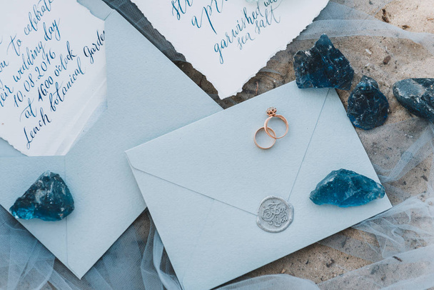 Hochzeits- und Verlobungsringe auf einem Umschlag neben Einladung und Speisekarte - Foto, Bild