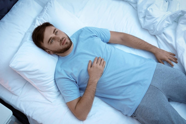 Mladý muž ležící v posteli a v noci. Porucha spánku - Fotografie, Obrázek