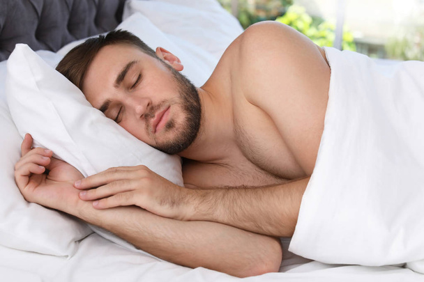 Young handsome man sleeping in bed at home. Early morning - Foto, imagen