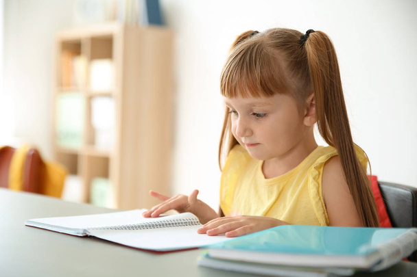 Cute little child doing assignment at desk in classroom. Elementary school - Photo, image