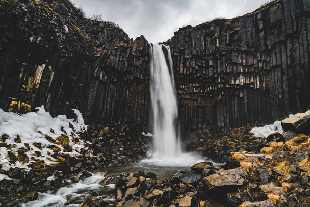 Dramatic morning view of famous Svartifoss Black Fall Waterfall. Colorful summer sunrise in Skaftafell, Vatnajokull National Park, Iceland, Europe. Artistic style post processed photo. - Фото, зображення