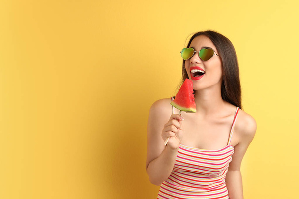 Beautiful young woman posing with watermelon on color background - Фото, изображение