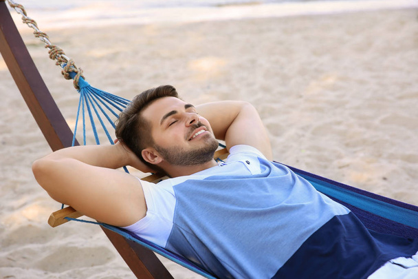 Young man lying in hammock at seaside. Summer vacation - Foto, Imagen
