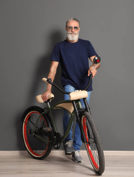 Portrait of handsome mature man with bicycle near color wall - Foto, Imagem