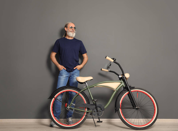 Portrait of handsome mature man with bicycle near color wall - Fotoğraf, Görsel