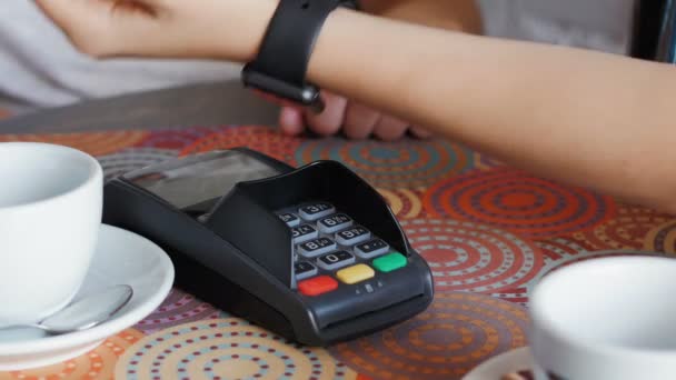 Mujer de negocios en la cafetería está pagando el precio mediante el uso de un reloj inteligente y terminal
 - Imágenes, Vídeo