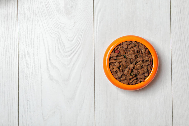 Schüssel mit Futter für Katze oder Hund auf Holzuntergrund. Haustierpflege - Foto, Bild