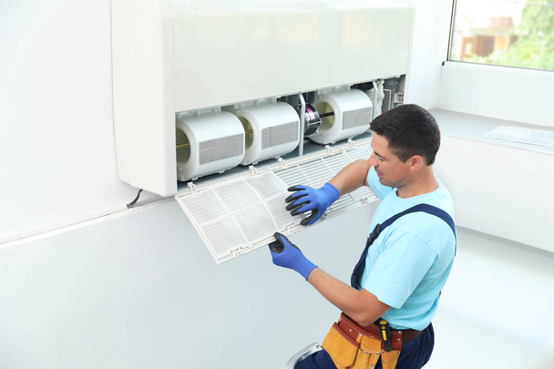 Male technician cleaning air conditioner indoors - Foto, Imagem
