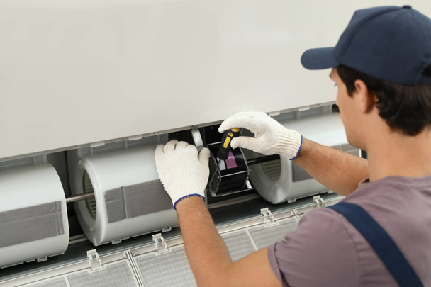 Male technician repairing air conditioner indoors - Foto, immagini