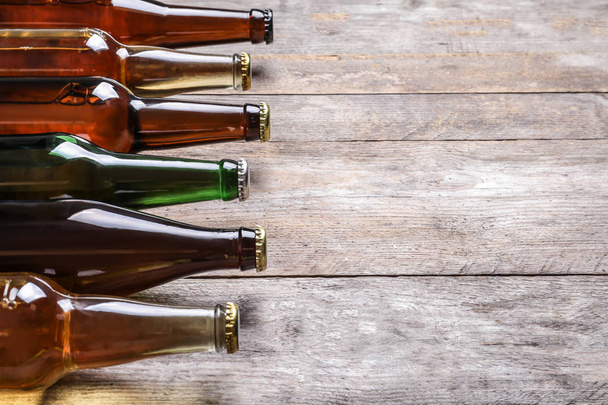 Bottles with different types of beer on wooden background - 写真・画像