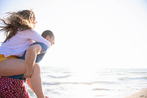  Mann trägt Frau auf dem Rücken am Strand - Foto, Bild