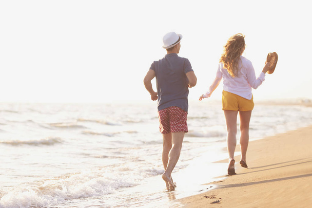 carefree man and woman walking at sea shore, back view - Foto, imagen