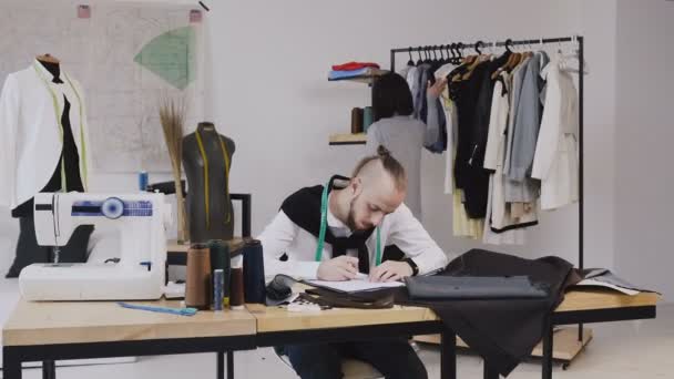 Two fashion designers working at the office with different tailoring tools sand clothes. Working on new collection together. Caucasian fashion designer and tailor - Video