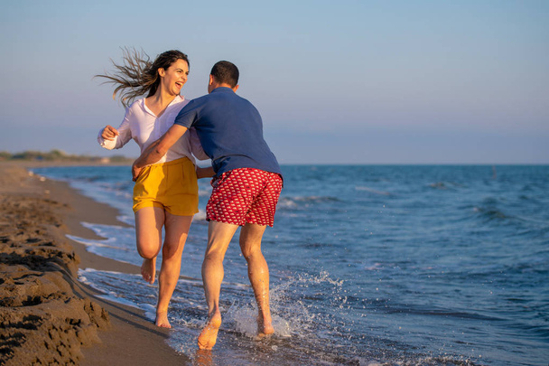 άνδρας και γυναίκα, περπατώντας στη θάλασσα στο ηλιοβασίλεμα - Φωτογραφία, εικόνα