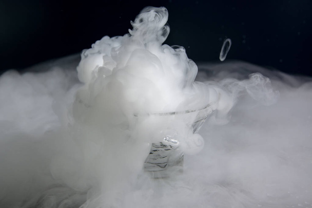 Jäädytetty kuiva jää valkoinen savuinen lasi pimeällä taustalla
 - Valokuva, kuva