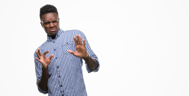 Jonge Afro-Amerikaanse man blauw shirt dragen walgen expressie, ontevreden en angstig walging gezicht doen omdat afkeer reactie. Handen aan de orde gesteld. Vervelend concept. - Foto, afbeelding