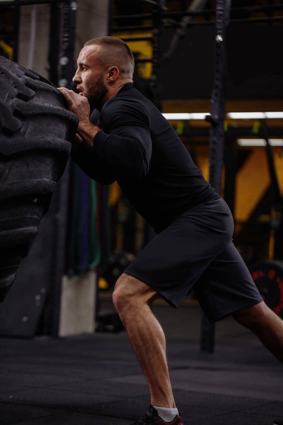 bearded powerful sportsman is training with big tire - Фото, изображение