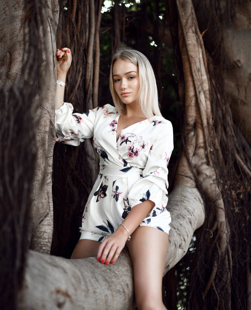 woman sitting in huge jungle trees with lianas in white casual dress - Foto, Imagem