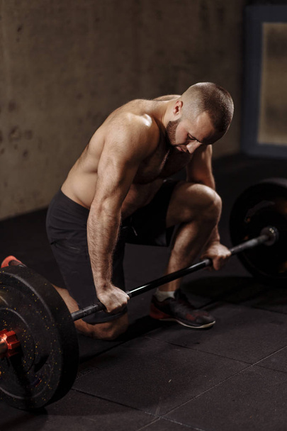 well-built strong man is working out with a heavy barbell - Photo, Image