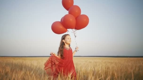 happy young girl with balloons running in the wheat field at sunset - Felvétel, videó