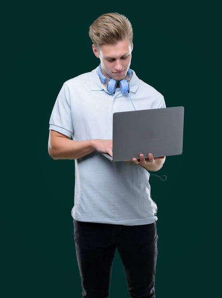 Joven hombre guapo rubio utilizando un ordenador portátil con una expresión de confianza en la cara inteligente pensando en serio
 - Foto, imagen