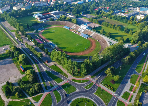 都市フットボール スタジアムの木々、道路と建物の空中写真. - 写真・画像
