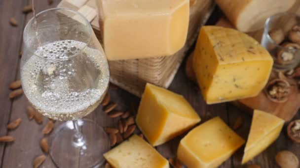 Ruokataidetta. Erilaisia juustoja kauniisti järjestetty puinen tausta. Huippunäkymä. Valkoviiniä kaadetaan lasiin. Erittäin hidasta. Hd
 - Materiaali, video