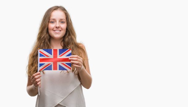 Молодая блондинка с флагом Великобритании со счастливым лицом стоя и улыбаясь с уверенной улыбкой, показывая зубы
 - Фото, изображение