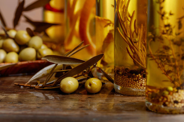 Groene olijven en flessen van olijfolie met kruiden en specerijen. Selectieve aandacht. - Foto, afbeelding