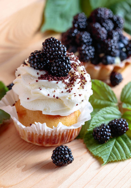 Blackberry smaczne ciasta z jagodami i krem na drewnianym stole. - Zdjęcie, obraz