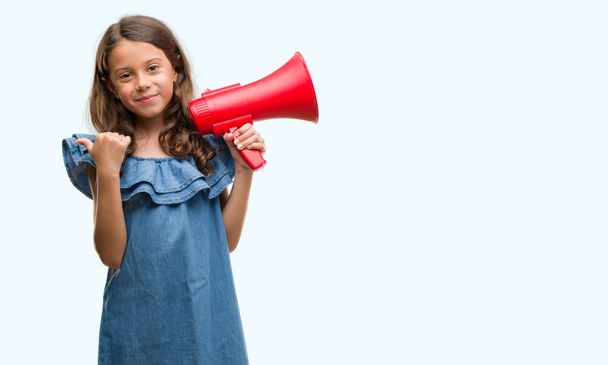 Brunette hispanic girl holding red megaphone pointing and showing with thumb up to the side with happy face smiling - Φωτογραφία, εικόνα