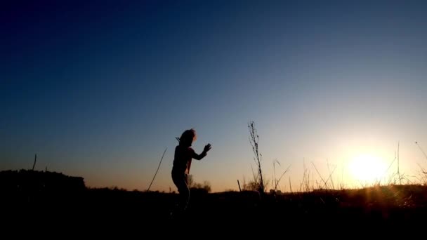 Silhouette of cheerful little girl running with small toy airplane - Footage, Video