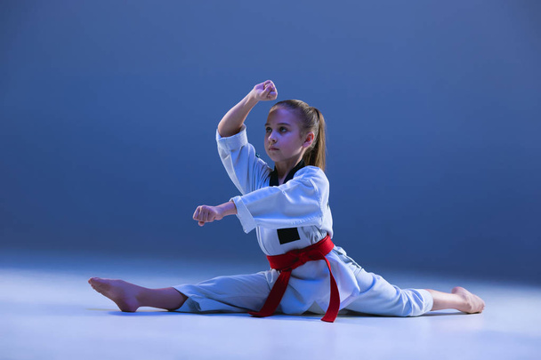 Young girl training karate on blue background - Фото, зображення