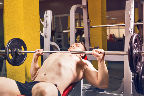 Спорт, фитнес, тренировки и люди концепция - Мускулистый человек делает тяжелые упражнения накачивания мышц на скамейке прессы
 - Фото, изображение