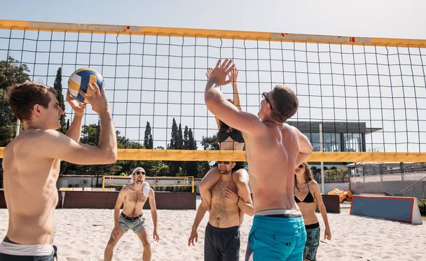 Group of resting playing volleyball on beach court - 写真・画像