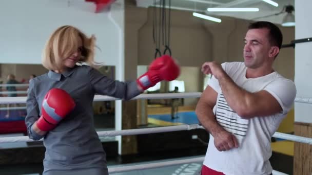 Beautiful woman in elegant dress training with coach at boxing ring - Záběry, video