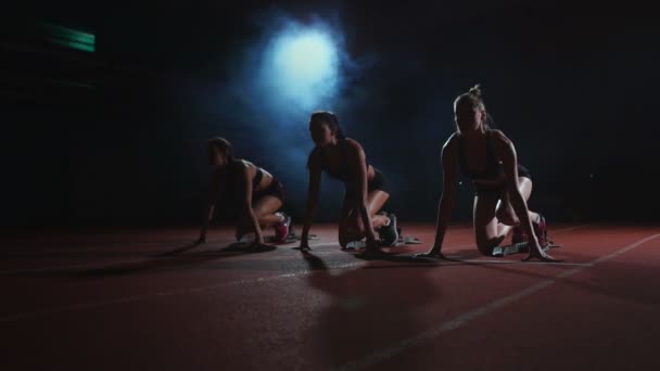 Läuferinnen auf der Leichtathletik-Bahn kauern vor einem Rennen in den Startlöchern. in Zeitlupe. - Filmmaterial, Video