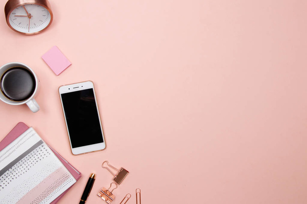 Schreibtisch mit Smartphone und anderen Büroutensilien auf rosa Hintergrund. Draufsicht mit Kopierraum, flache Lage. - Foto, Bild