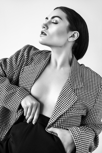 seductive half naked woman posing in retro jacket, isolated on grey, black and white - 写真・画像