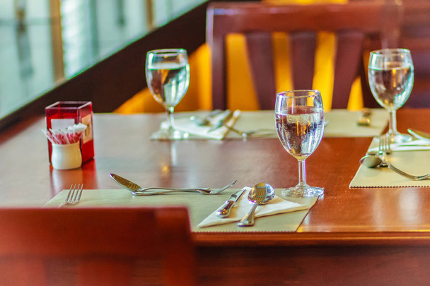 Vasos, cuchara, rana, cuchillo, servilleta y platos en la mesa para reuniones y celebraciones de decoración
. - Foto, Imagen