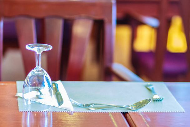 Vasos, cuchara, rana, cuchillo, servilleta y platos en la mesa para reuniones y celebraciones de decoración
. - Foto, imagen