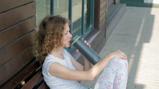 Sportif kadın ağır çekimde bir parkta bir şişe su içme - Video, Çekim