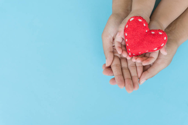 Bovenaanzicht van volwassene en kind met rood hart in handen, gelukkig familierelaties, Valentijnsdag, Moederdag, liefde en gezondheidszorg concept. - Foto, afbeelding