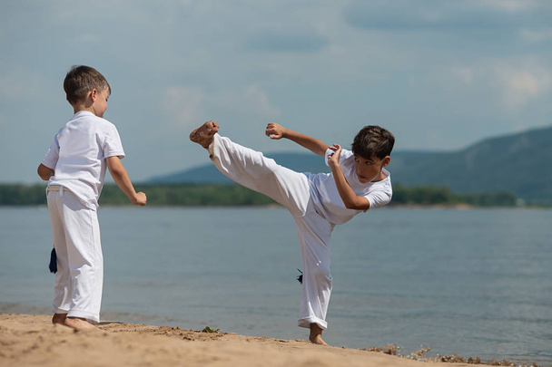 Training of two children on the beach, on the sea: capoeira, sports - Φωτογραφία, εικόνα