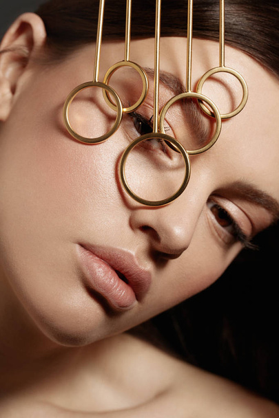 Beauty portrait of young brunette model with golden jewelry accessories on face, close up - Fotografie, Obrázek