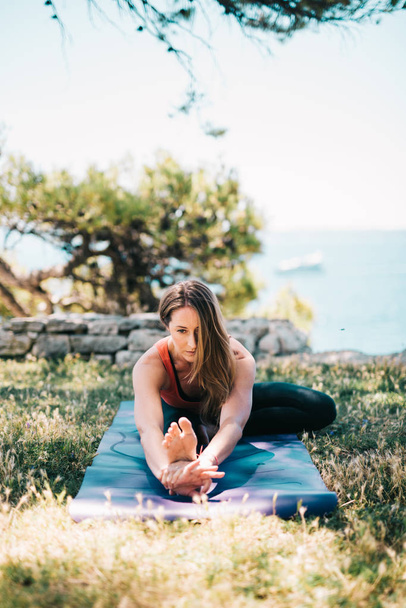 Mujer practicando yoga en parque junto al mar
 - Foto, imagen