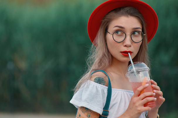A Young stylish woman having a refreshing drink while looking cu - Photo, Image