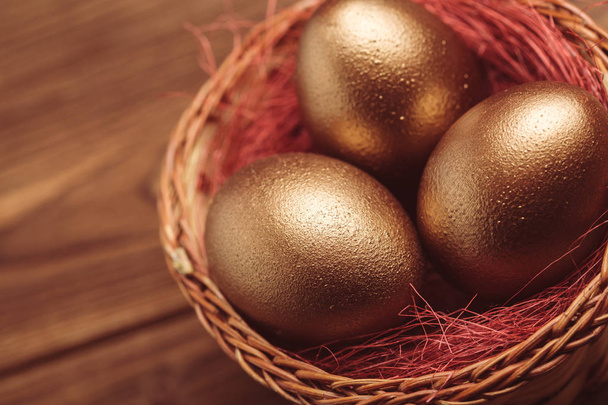 gold eggs on wooden table - Фото, зображення