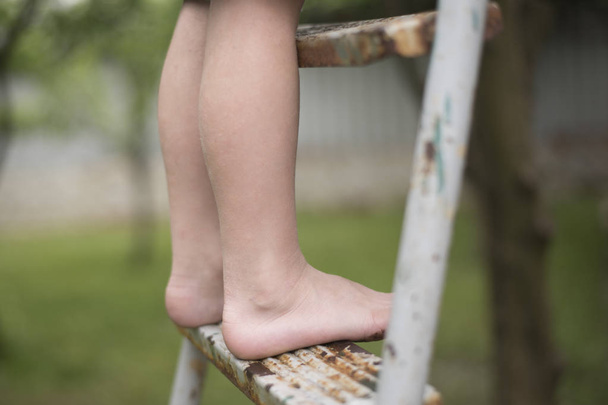 Children's bare feet on the ladder. Close-up. Outdoors - Foto, imagen