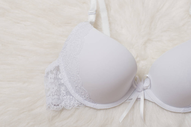 Fashionable concept. Female underwear. White bra with lace on white fur.  - Photo, Image